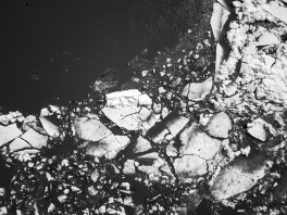 A black and white image of light fractured stone pieces on a dark background.