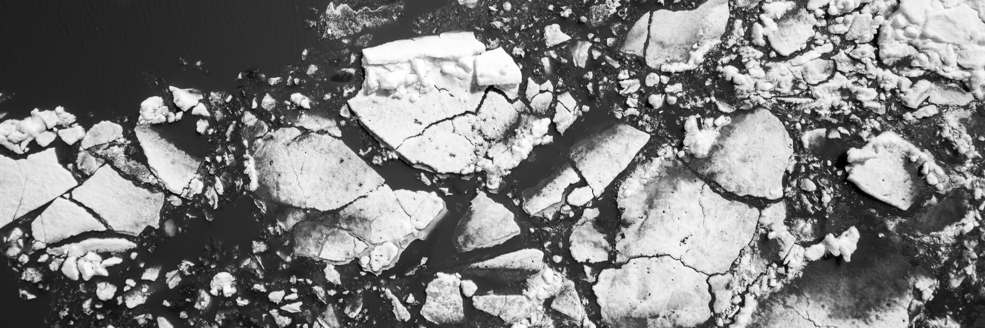 A black and white image of light fractured stone pieces on a dark background.